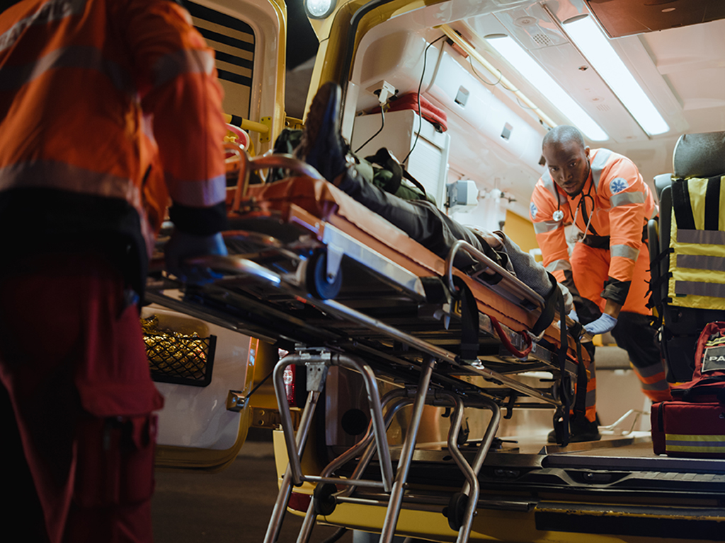 Team of EMS Paramedics React Quick to Bring Injured Patient to Healthcare Hospital and Get Him Out of Ambulance on a Stretcher. Emergency Care Assistants Help Young Man to Stay Alive After Accident.